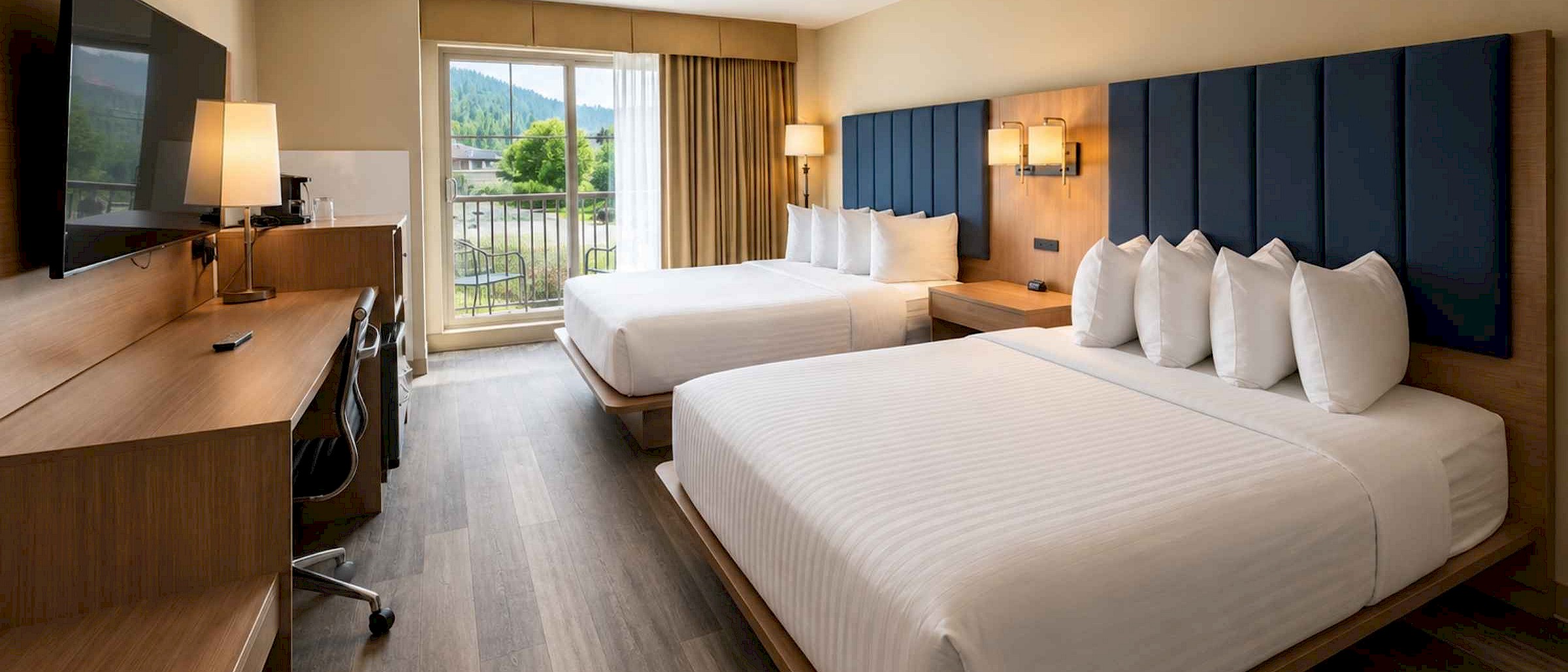 Modern hotel room with two queen beds, dark blue headboards, and a private balcony at St. Eugene Resort