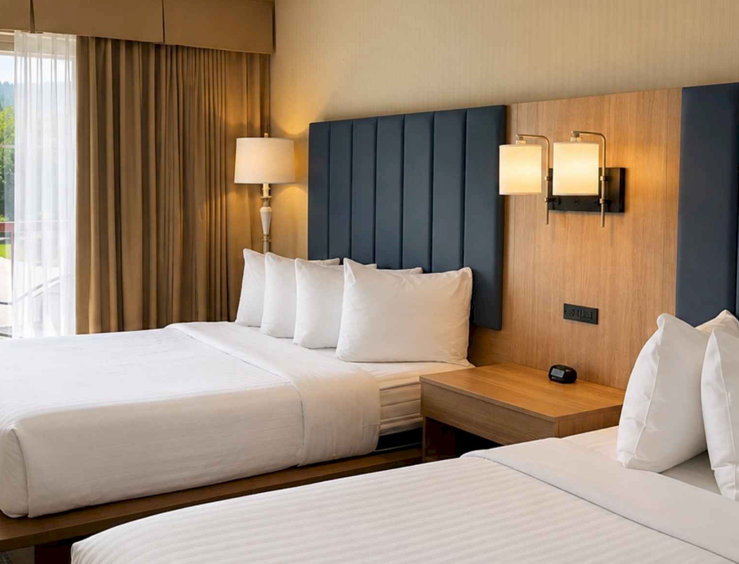 Two queen beds in a brightly lit hotel room with a balcony view.